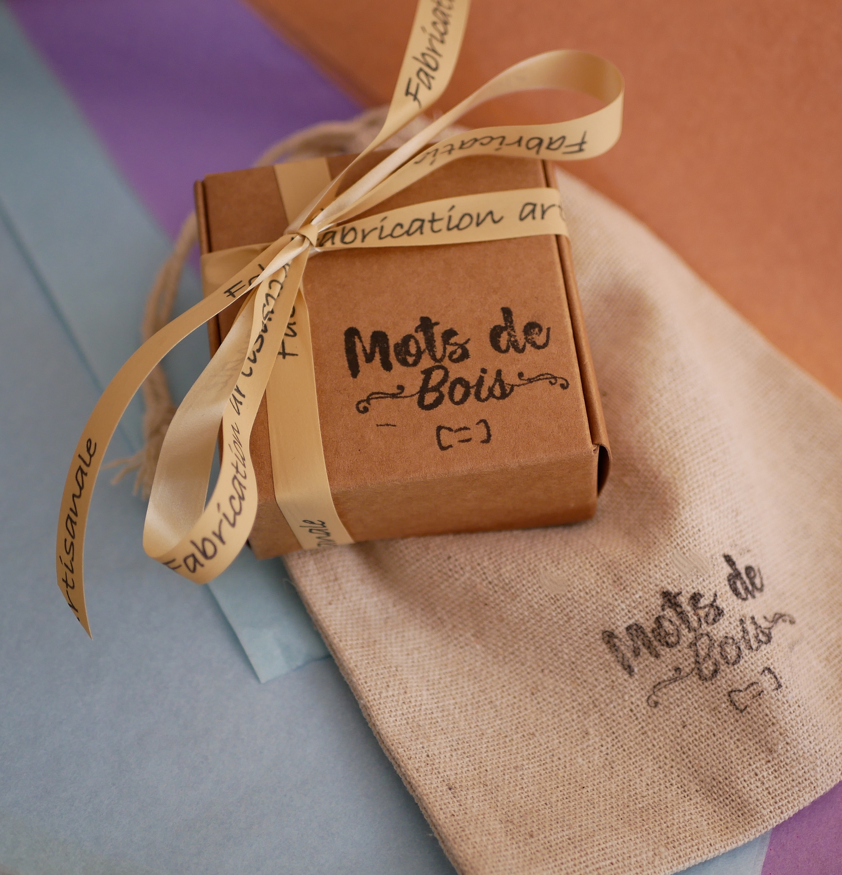 Coffret cadeau artisanal Mots de Bois avec ruban personnalisé.