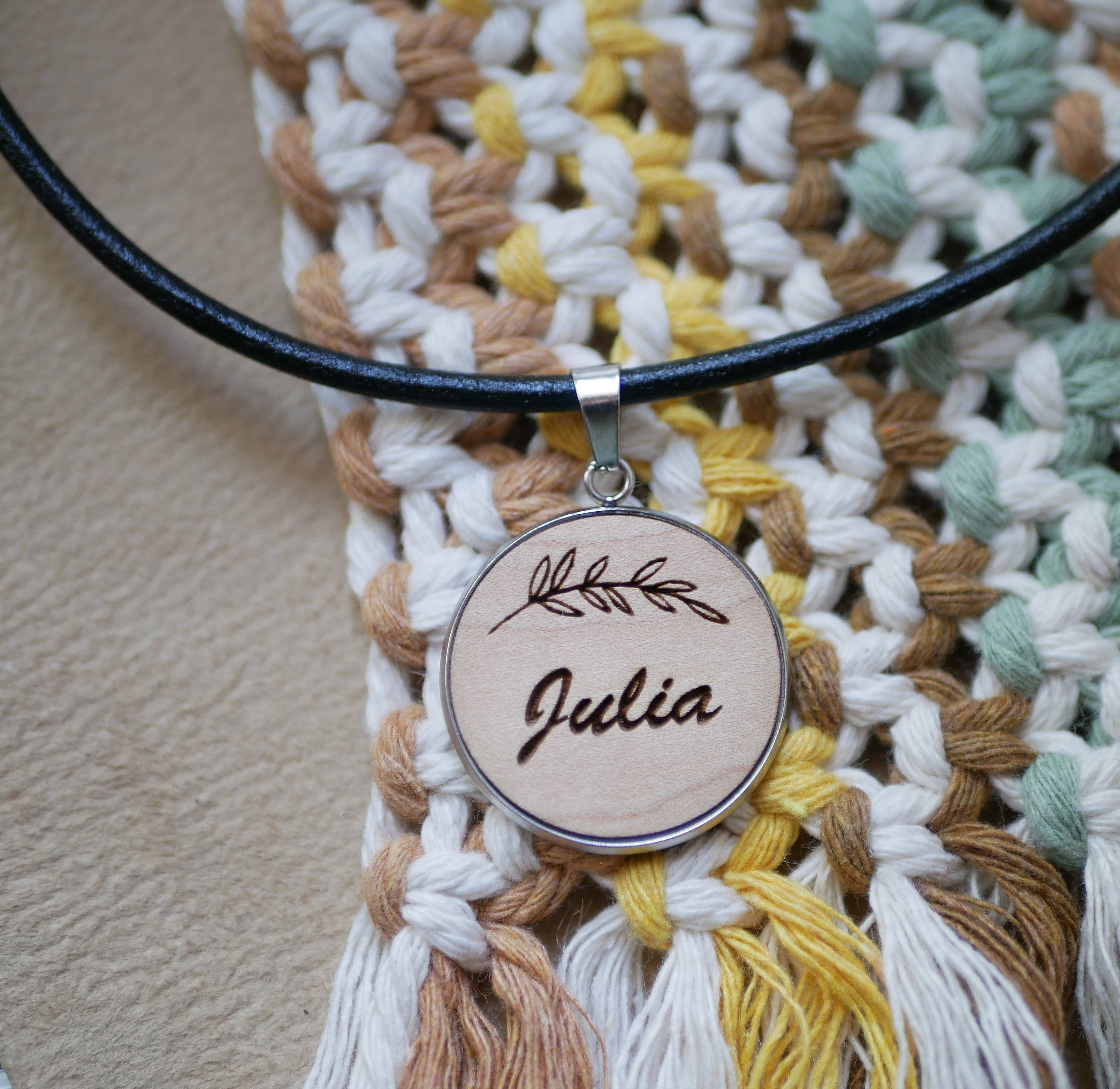 Médaillon en bois gravé personnalisé sur collier en cuir noir.